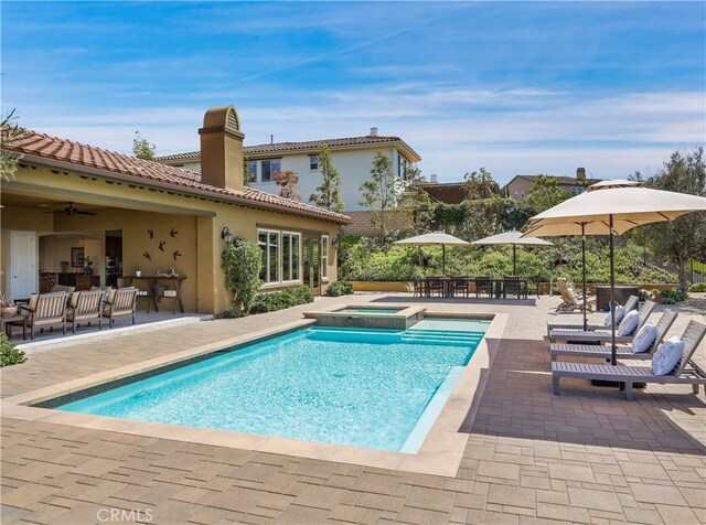 view of pool featuring ceiling fan, a pool with connected hot tub, a patio area, and outdoor lounge area