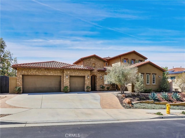 mediterranean / spanish-style house featuring a garage, concrete driveway, a tile roof, and stone siding