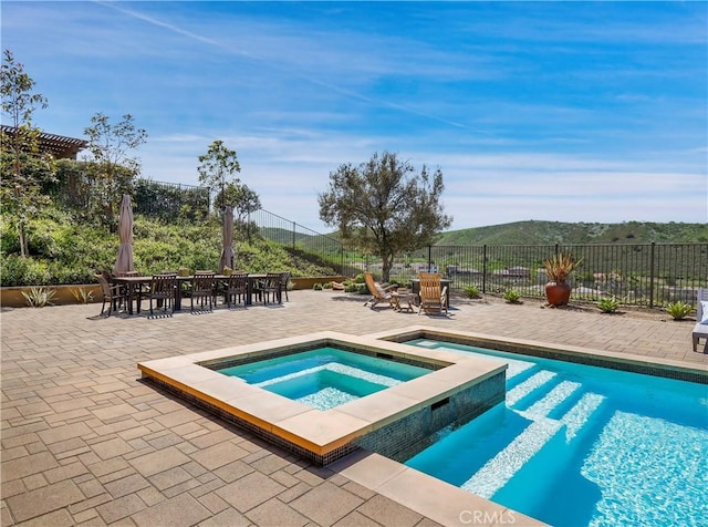 view of swimming pool with fence, a fenced in pool, an in ground hot tub, outdoor dining area, and a patio