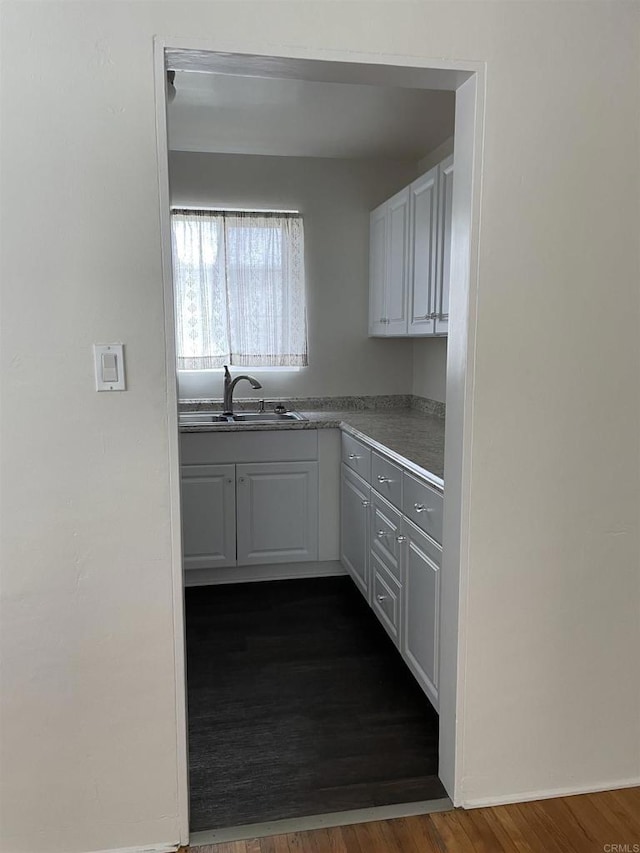 kitchen featuring white cabinets, dark wood-style floors, and a sink