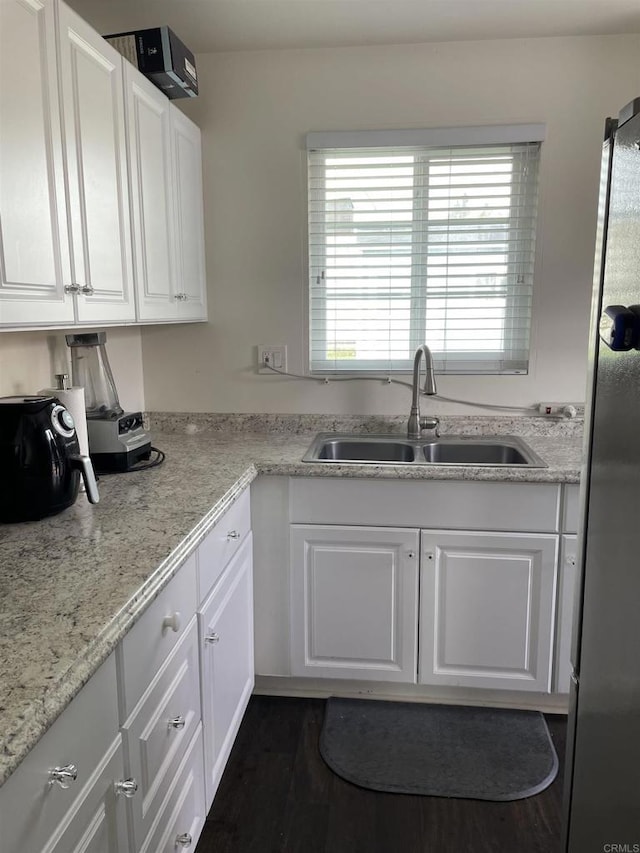 kitchen featuring white cabinetry, light countertops, freestanding refrigerator, and a sink