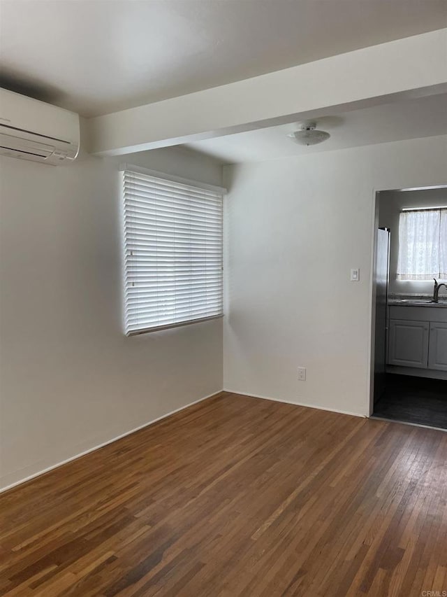 unfurnished room with a sink, dark wood-style flooring, and a wall unit AC