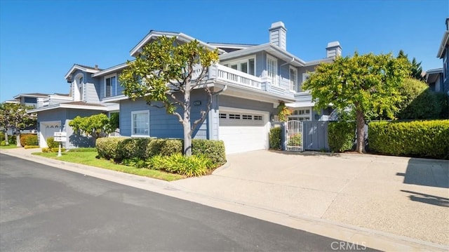 view of front of house with an attached garage, concrete driveway, a balcony, and a gate