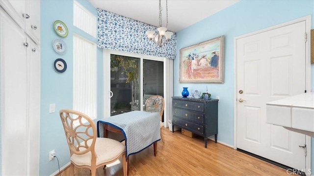 living area with an inviting chandelier, light wood-style floors, and baseboards