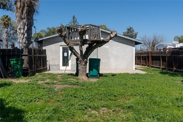 back of property with a yard, stucco siding, and fence