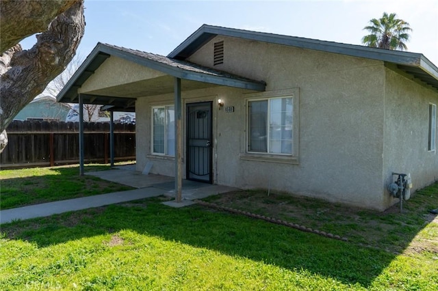 view of front of home with a patio, a front yard, fence, and stucco siding