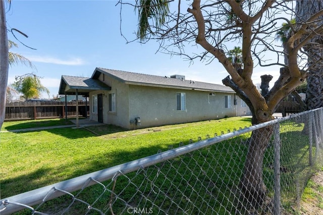 back of property featuring stucco siding, a lawn, a fenced backyard, and a shingled roof