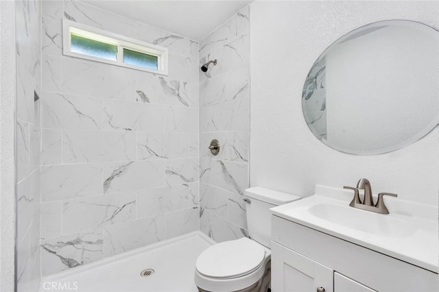 bathroom featuring toilet, vanity, and a tile shower