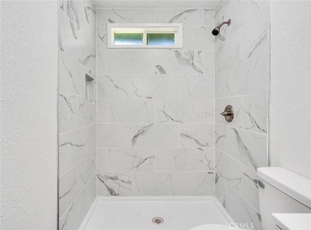 full bathroom featuring toilet, a stall shower, and a textured wall