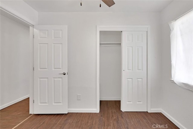 unfurnished bedroom with a closet, baseboards, and wood finished floors