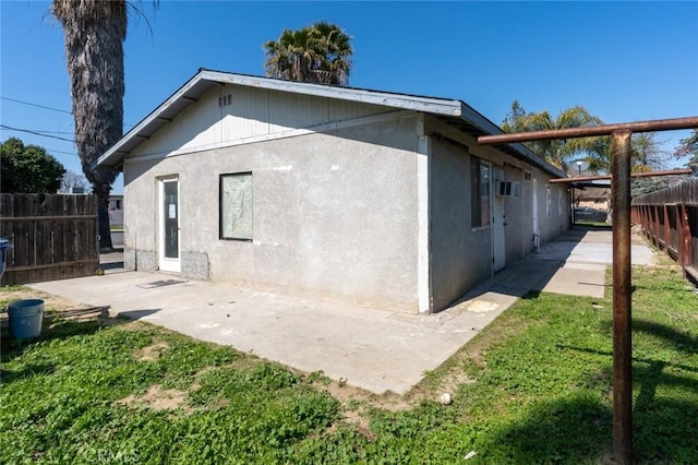 rear view of property featuring a patio, fence, and stucco siding