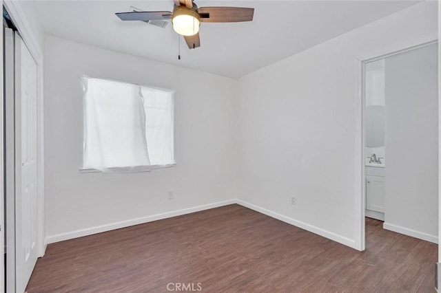 unfurnished bedroom with a sink, wood finished floors, a closet, baseboards, and ceiling fan