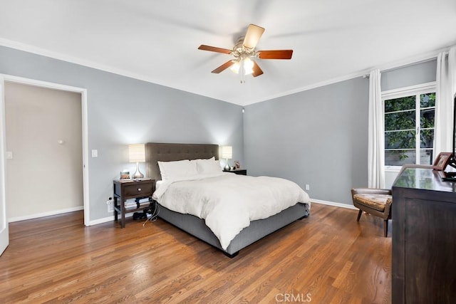 bedroom featuring ceiling fan, wood finished floors, baseboards, and ornamental molding