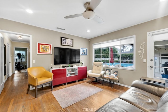 living room with ceiling fan, visible vents, baseboards, and wood finished floors