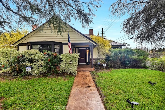 view of front of home featuring a chimney and a front yard