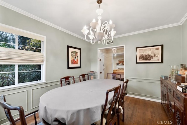 dining area featuring dark wood finished floors, an inviting chandelier, wainscoting, and ornamental molding