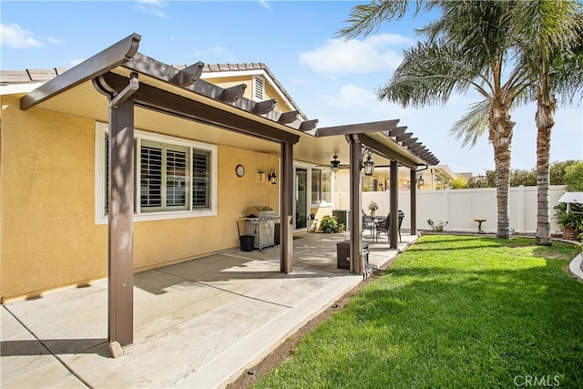 rear view of property featuring fence, a yard, ceiling fan, stucco siding, and a patio area