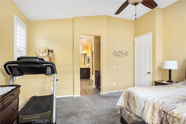 carpeted bedroom featuring ensuite bath and baseboards