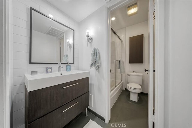 bathroom featuring vanity, visible vents, tile patterned flooring, toilet, and combined bath / shower with glass door