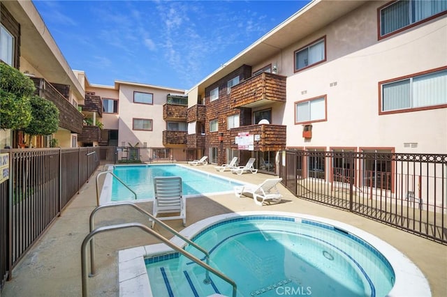 community pool with a community hot tub, a patio, and fence