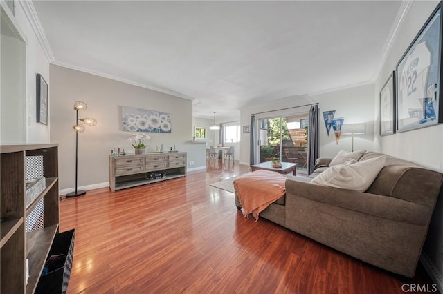 living area with baseboards, wood finished floors, and ornamental molding