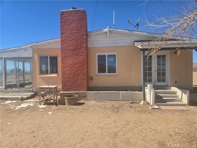 back of house with entry steps and a chimney