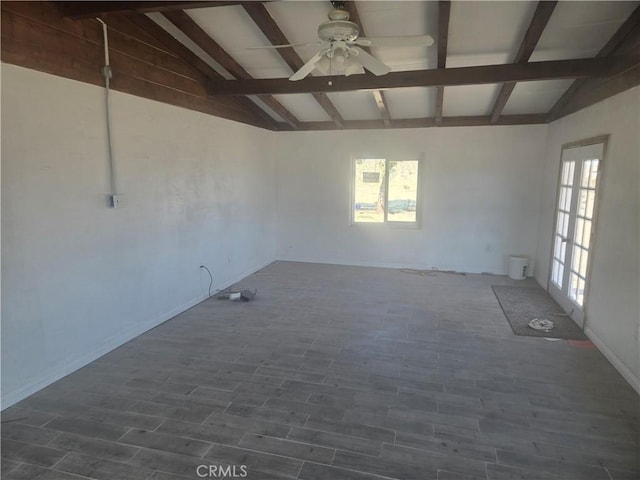 unfurnished room featuring a ceiling fan, lofted ceiling with beams, plenty of natural light, and dark wood-style floors