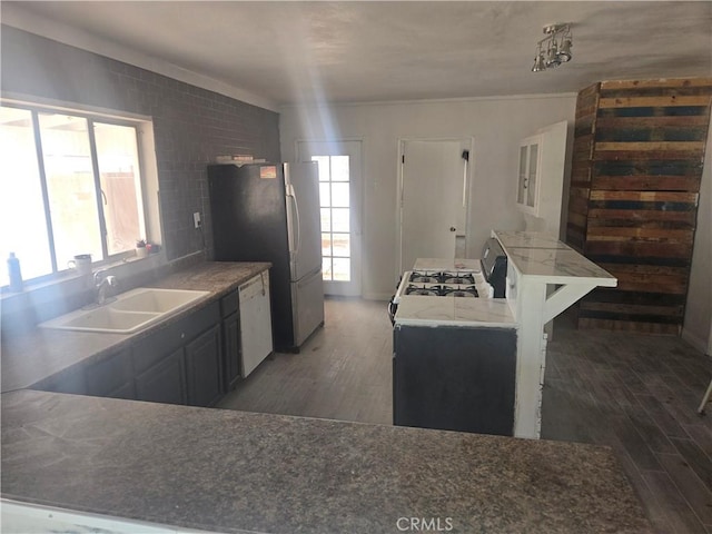 kitchen featuring white appliances, light wood-type flooring, a wealth of natural light, and a sink