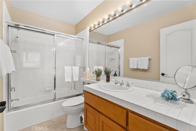 bathroom featuring tile patterned floors, combined bath / shower with glass door, toilet, and vanity