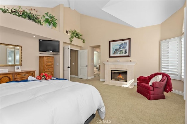 carpeted bedroom with visible vents, high vaulted ceiling, a tiled fireplace, ensuite bath, and baseboards