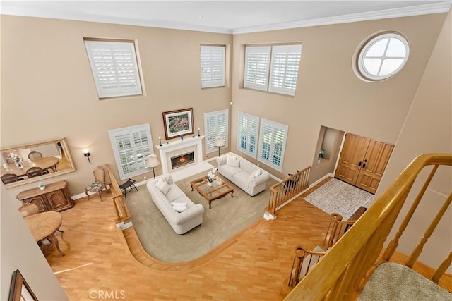 living area featuring crown molding, stairway, light wood finished floors, and a high end fireplace