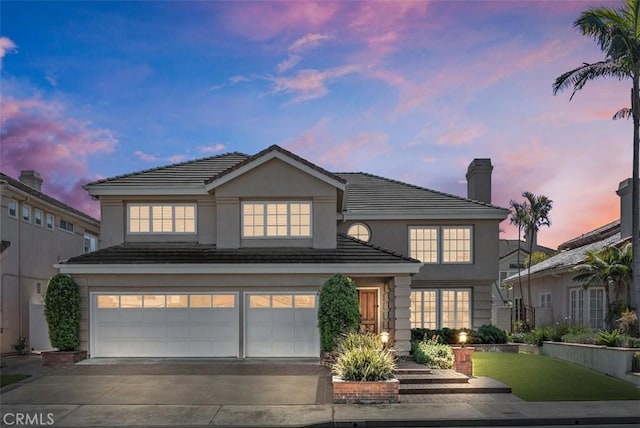 traditional-style home with stucco siding, an attached garage, a tile roof, and driveway