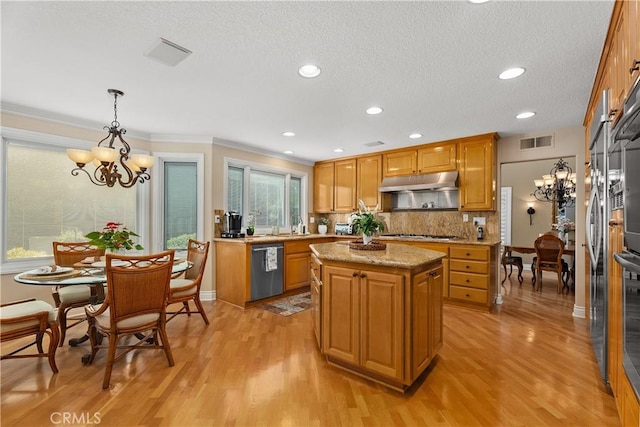 kitchen featuring visible vents, under cabinet range hood, a kitchen island, backsplash, and stainless steel appliances