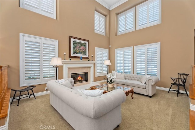 living room with a glass covered fireplace, light colored carpet, crown molding, and baseboards