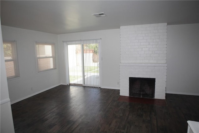 unfurnished living room featuring visible vents, baseboards, a brick fireplace, and wood finished floors