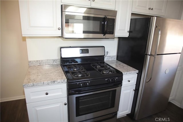 kitchen with stainless steel appliances, dark wood finished floors, and white cabinetry