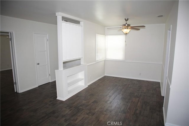 spare room featuring baseboards, dark wood-style floors, visible vents, and ceiling fan