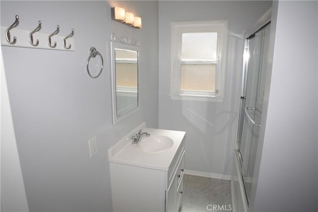 bathroom with vanity, baseboards, and a shower with shower door