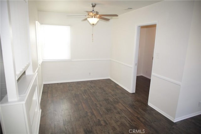 empty room featuring ceiling fan, dark wood-type flooring, and baseboards