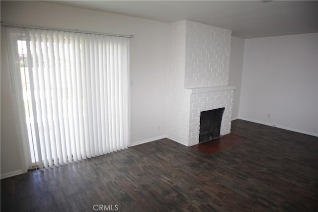 unfurnished living room with wood finished floors, a fireplace, and baseboards