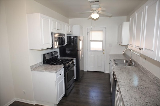 kitchen with a sink, baseboards, appliances with stainless steel finishes, white cabinetry, and dark wood-style flooring