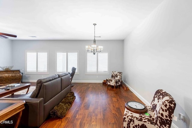 living room with dark wood-style floors, ceiling fan with notable chandelier, and baseboards