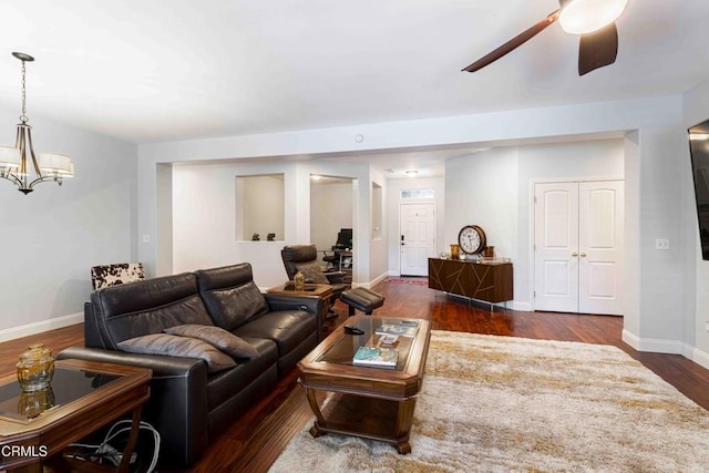 living room with baseboards, wood finished floors, and ceiling fan with notable chandelier