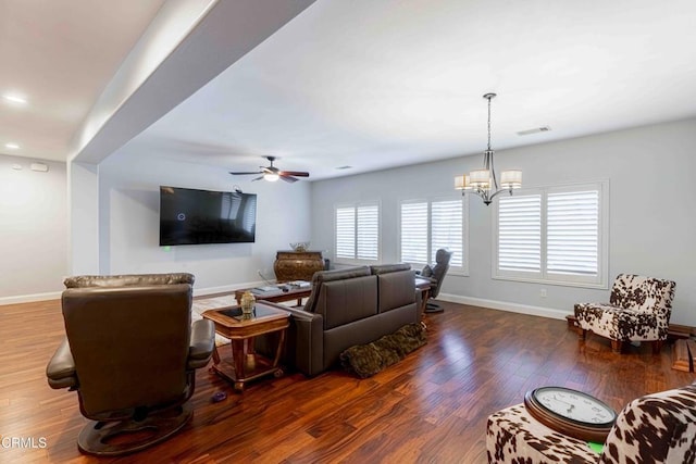 living room featuring ceiling fan with notable chandelier, wood finished floors, visible vents, and baseboards