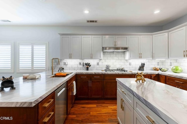 kitchen with under cabinet range hood, visible vents, appliances with stainless steel finishes, and a sink