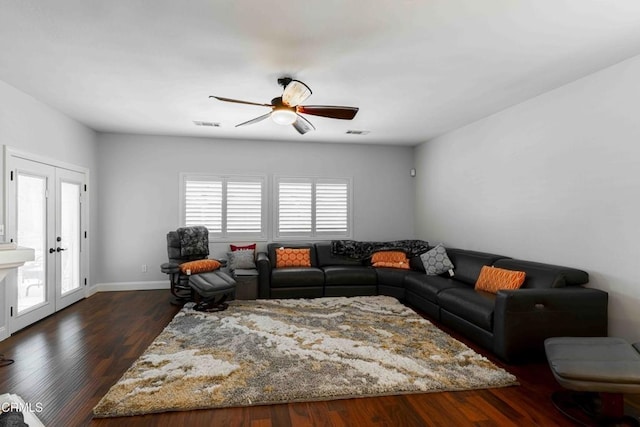 living room with visible vents, baseboards, ceiling fan, and dark wood-style flooring