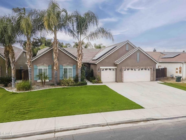 ranch-style home with a front lawn, an attached garage, roof mounted solar panels, and stucco siding