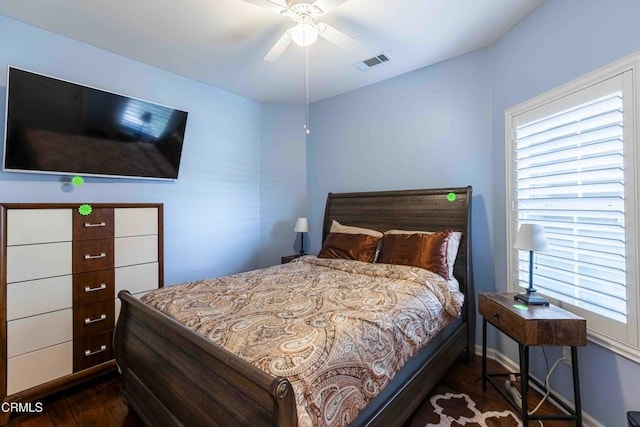 bedroom with a ceiling fan, dark wood-style floors, visible vents, and baseboards