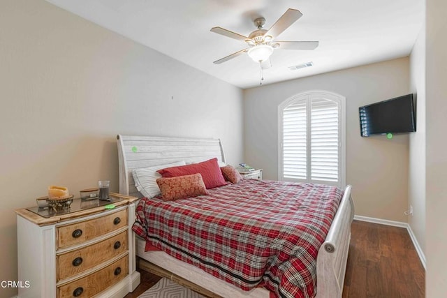 bedroom featuring dark wood finished floors, baseboards, visible vents, and a ceiling fan