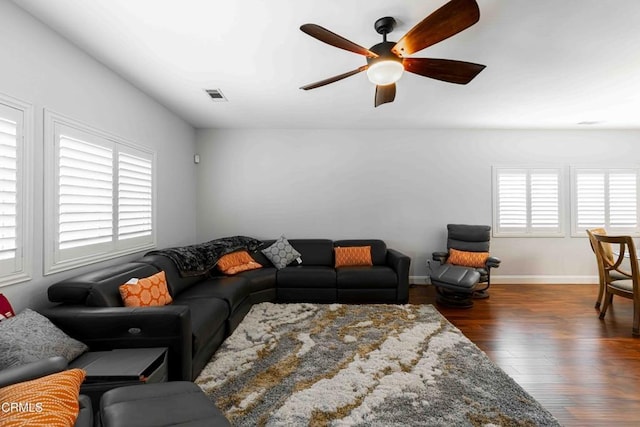 living room featuring ceiling fan, visible vents, baseboards, and wood finished floors